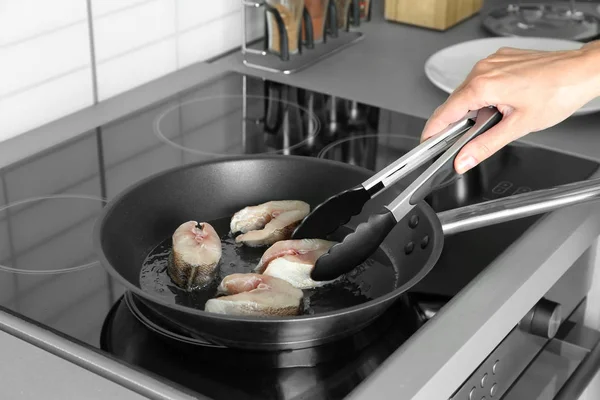 Donna che frigge bistecche di pesce su pentola in cucina — Foto Stock