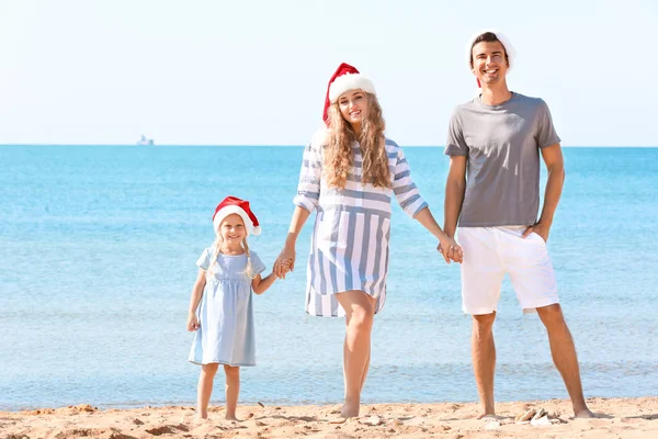 年轻的夫妇在海滩上的女孩。圣诞节庆祝概念 — 图库照片