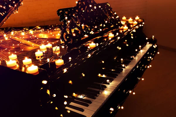 Vintage piano with Christmas lights and candles in dark room — Stock Photo, Image