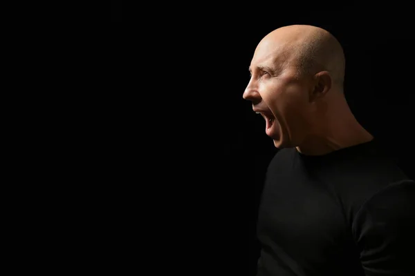 Känslomässiga skallig man i t-shirt på svart bakgrund — Stockfoto