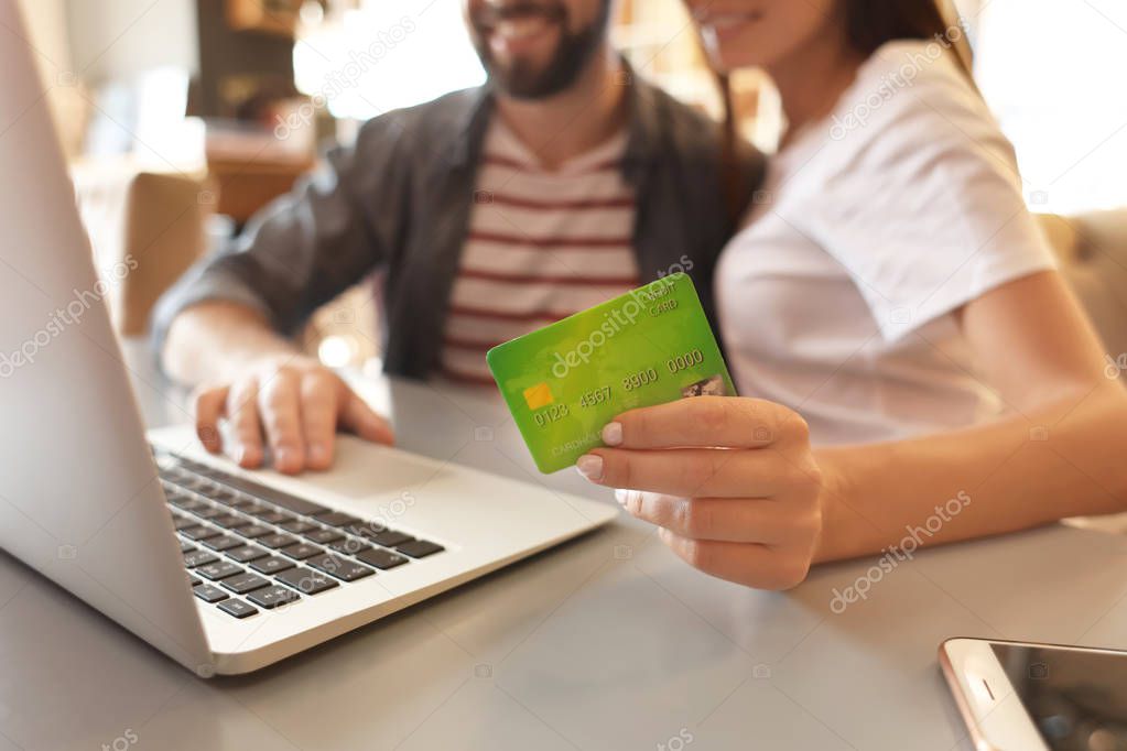 Couple with laptop and credit card indoors. Internet shopping concept