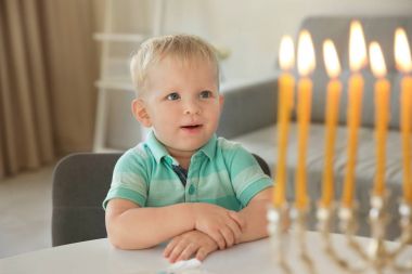 Sevimli çocuk dokuz dallı menorah evde masaya oturan