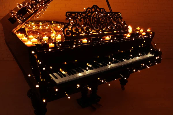 Vintage piano with Christmas lights and candles in dark room — Stock Photo, Image