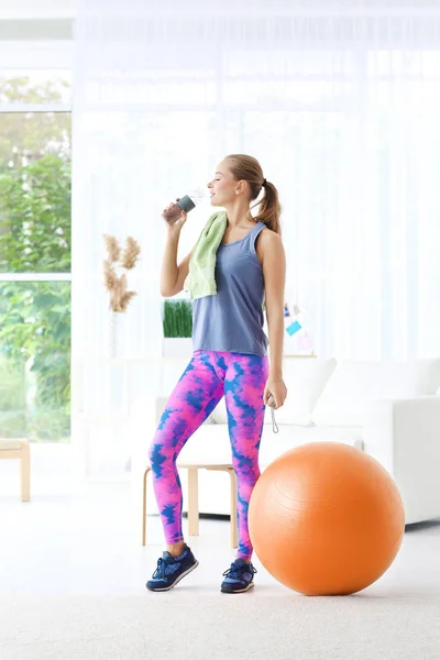 Junge sportliche Frau trinkt zu Hause Wasser — Stockfoto