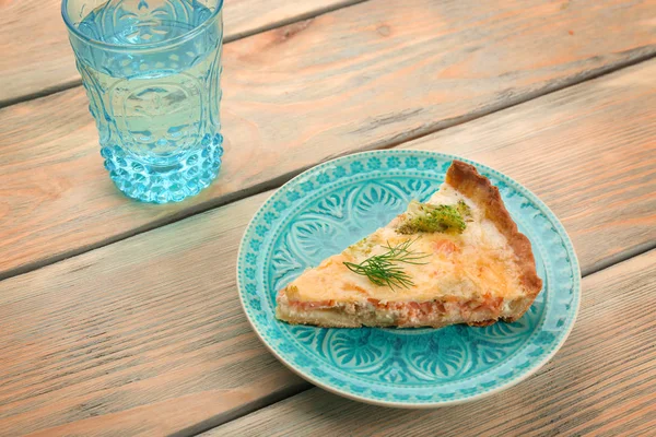 Plaat met stuk heerlijke zalm quiche op tafel — Stockfoto