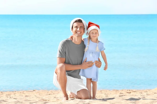 年轻的父亲与可爱的女孩在海滩上。圣诞节庆祝概念 — 图库照片