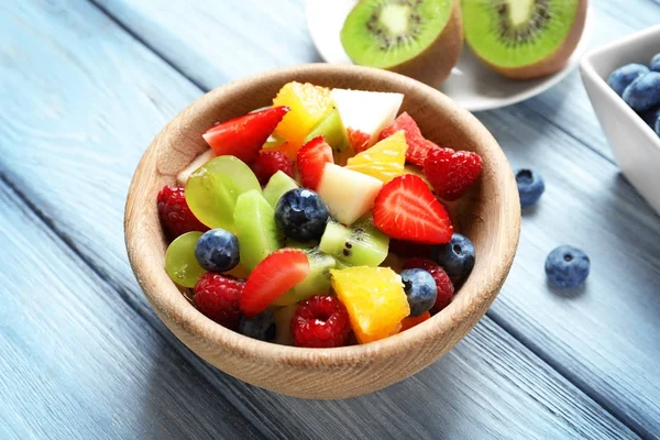 Bowl with delicious fruit salad on wooden background — Stock Photo, Image