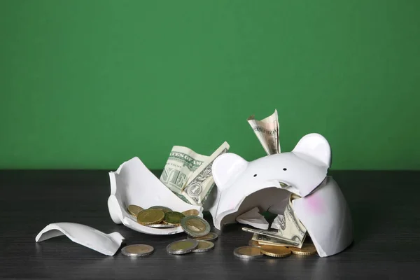Разбитая копилка с деньгами на столе на цветном фоне — стоковое фото
