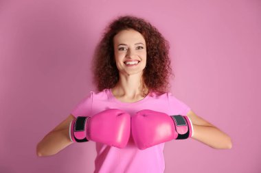 Pembe tişört ve boks eldivenleri renk arka plan üzerinde bir genç kadın. Meme Kanseri Bilinçlendirme kavramı