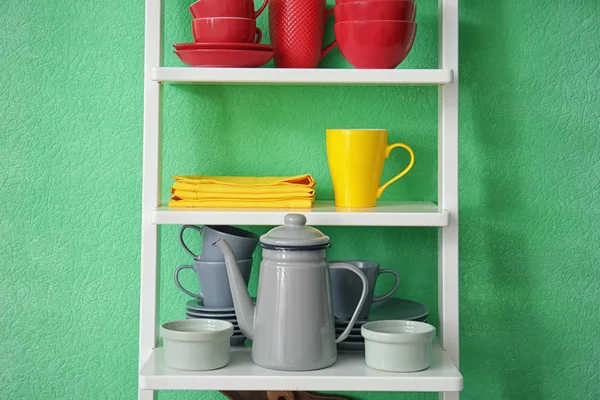 Witte rekken eenheid met keramische servies in de buurt van kleur muur — Stockfoto