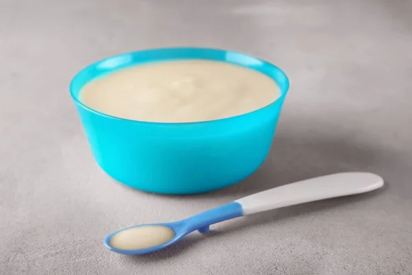 Cuillère et bol avec du porridge pour bébé sur la table — Photo