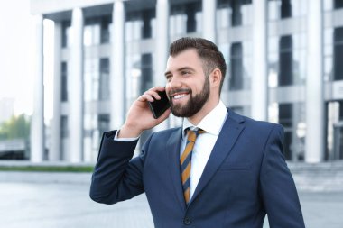 Cep telefonu açık havada üzerinde konuşurken yakışıklı başarılı iş adamı