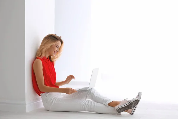 Hübsche Frau mit modernem Laptop auf dem Boden sitzend — Stockfoto
