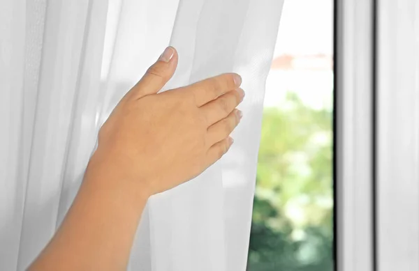 Mujer sosteniendo cortinas modernas en la habitación —  Fotos de Stock