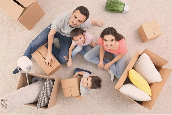 Gelukkige familie zittend op tapijt in kamer nieuwe thuis — Stockfoto