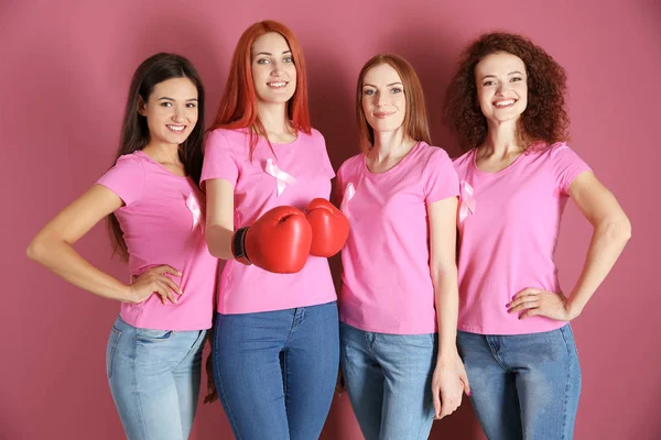 Mujeres jóvenes en camisetas de color rosa sobre fondo de color. Concepto de conciencia sobre el cáncer de mama — Foto de Stock