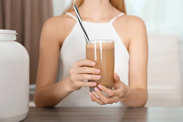 Woman holding glass with protein shake at table — Stock Photo, Image