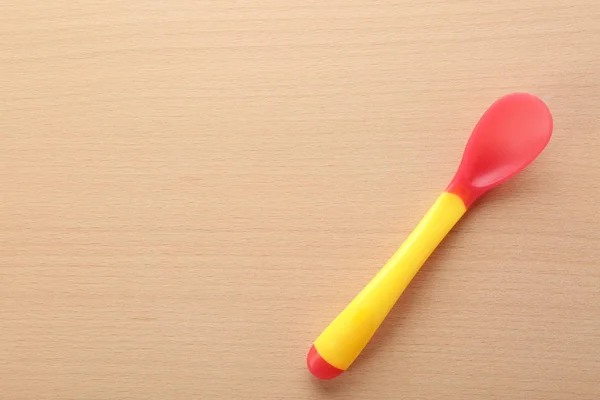 Colorful spoon for baby on wooden table — Stock Photo, Image