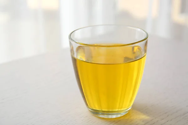 Glass with oil on light background — Stock Photo, Image