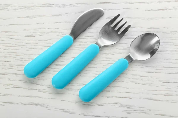 Utensilios de alimentación coloridos para bebé en mesa de madera —  Fotos de Stock