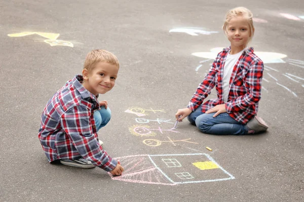 Pequeños niños dibujando casa y familia con tiza sobre asfalto — Foto de Stock