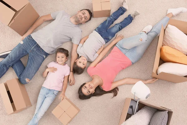 Glückliche Familie liegt auf Teppich in Zimmer im neuen Zuhause — Stockfoto