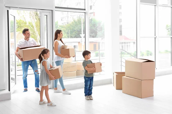Familia feliz con cajas de mudanza entrando en casa nueva — Foto de Stock