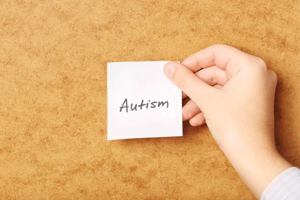 Donna che tiene un foglio di carta con scritto "Autismo" su sfondo impiallacciato — Foto Stock