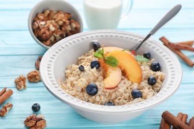Bir kase yulaf ezmesi, şeftali ve çilek masada
