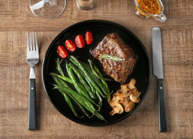 Lezzetli ızgara biftek ve ahşap masa sebze ile plaka