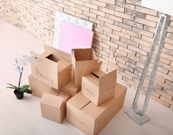 Mover concepto de casa. Cajas de cartón en el suelo en habitación vacía —  Fotos de Stock