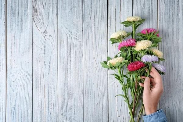 Mulher que arranja buquê de flores de crisântemo na mesa de madeira — Fotografia de Stock