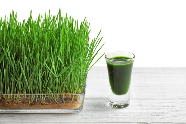 Composition with shot of healthy wheat grass juice on white wooden table — Stock Photo, Image