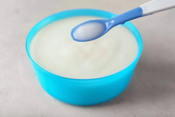 Spoon of baby porridge over bowl on table — Stock Photo, Image