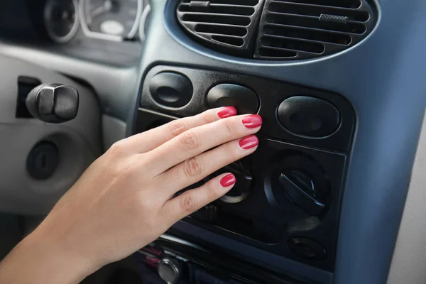 Frau drückt Taste auf Armaturenbrett im Auto — Stockfoto