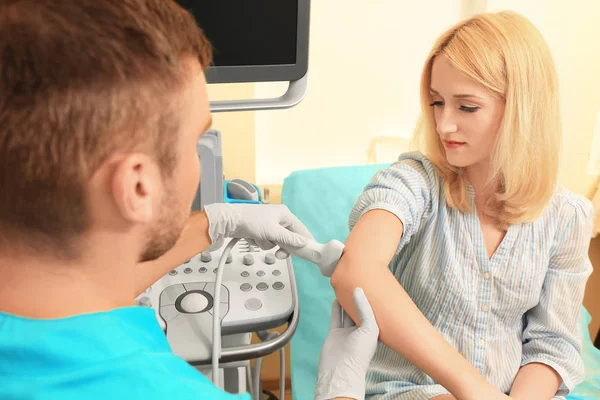 Doctor conducting ultrasound examination of patient's elbow in clinic — Stock Photo, Image