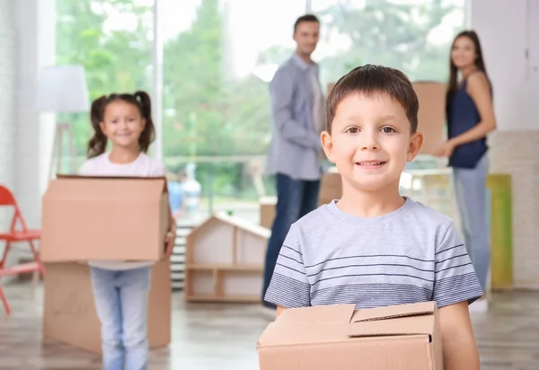 Lindo niño pequeño con caja móvil en la habitación en el nuevo hogar — Foto de Stock