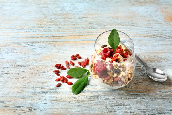 Sobremesa deliciosa com bagas de goji em vidro no fundo de madeira — Fotografia de Stock