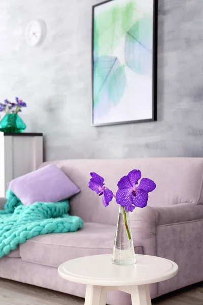 Lila accent in moderne interieur. Tabel met bloemen en comfortabele bank in de woonkamer — Stockfoto