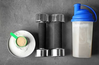 Protein içeceği, toz ve masada dumbbells ile şişe