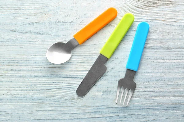 Utensilios de alimentación coloridos para bebé en mesa de madera —  Fotos de Stock