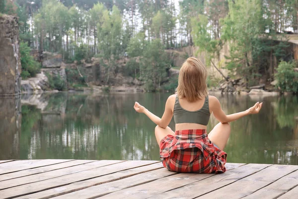 Młoda piękna kobieta siedzi w pobliżu jeziora, w lesie — Zdjęcie stockowe