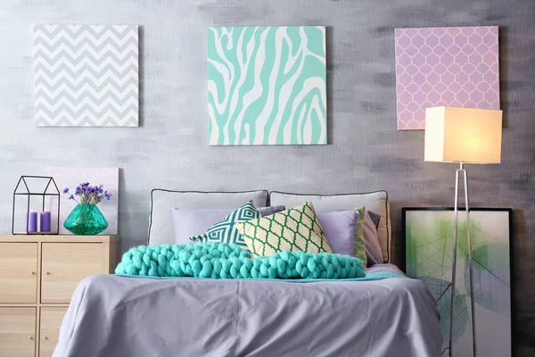 Acento lila en el interior moderno. Cómoda cama con almohadas y cuadros en la habitación — Foto de Stock