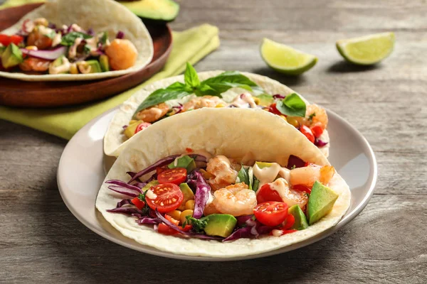 Placa con deliciosos tacos de camarones sobre mesa de madera —  Fotos de Stock