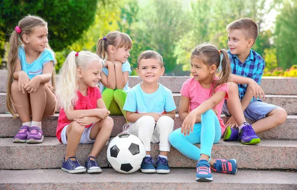 Милые маленькие дети с мячом сидят на лестнице в городском парке — стоковое фото