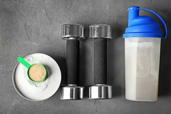 Flasche mit Proteinshake, Pulver und Kurzhanteln auf dem Tisch — Stockfoto