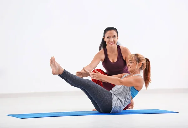 Donna matura con istruttore di yoga personale al chiuso — Foto Stock
