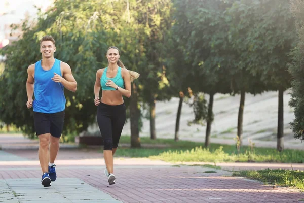 Jeune couple sportif courant dans un parc verdoyant — Photo