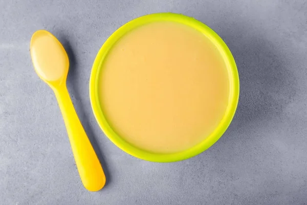Tigela e colher com mingau de cereal bebê na mesa — Fotografia de Stock