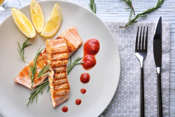 Teller mit leckeren Lachsscheiben und Soße auf dem Tisch — Stockfoto